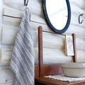 flax linen hand towel hanging from metal hook in log house