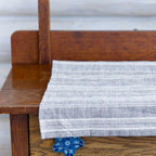 heather gray and white stripe flax linen hand towel laying flat on wood cabinet