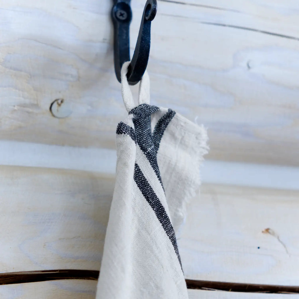antique white flax linen hand towel hanging from hook.