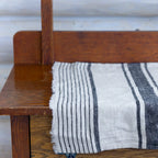 white and black stripe flax linen hand towel laying flat on wood cabinet