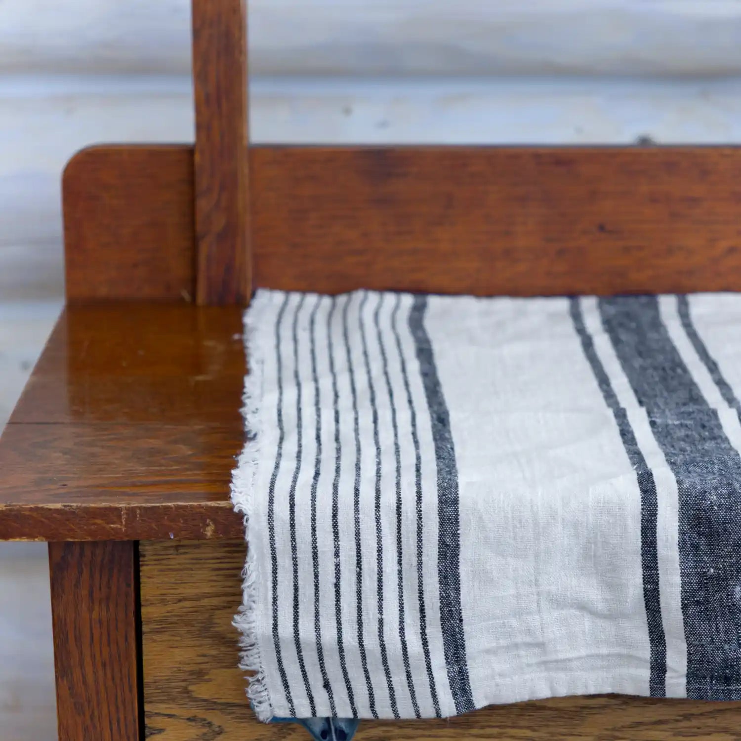 white and black stripe flax linen hand towel laying flat on wood cabinet