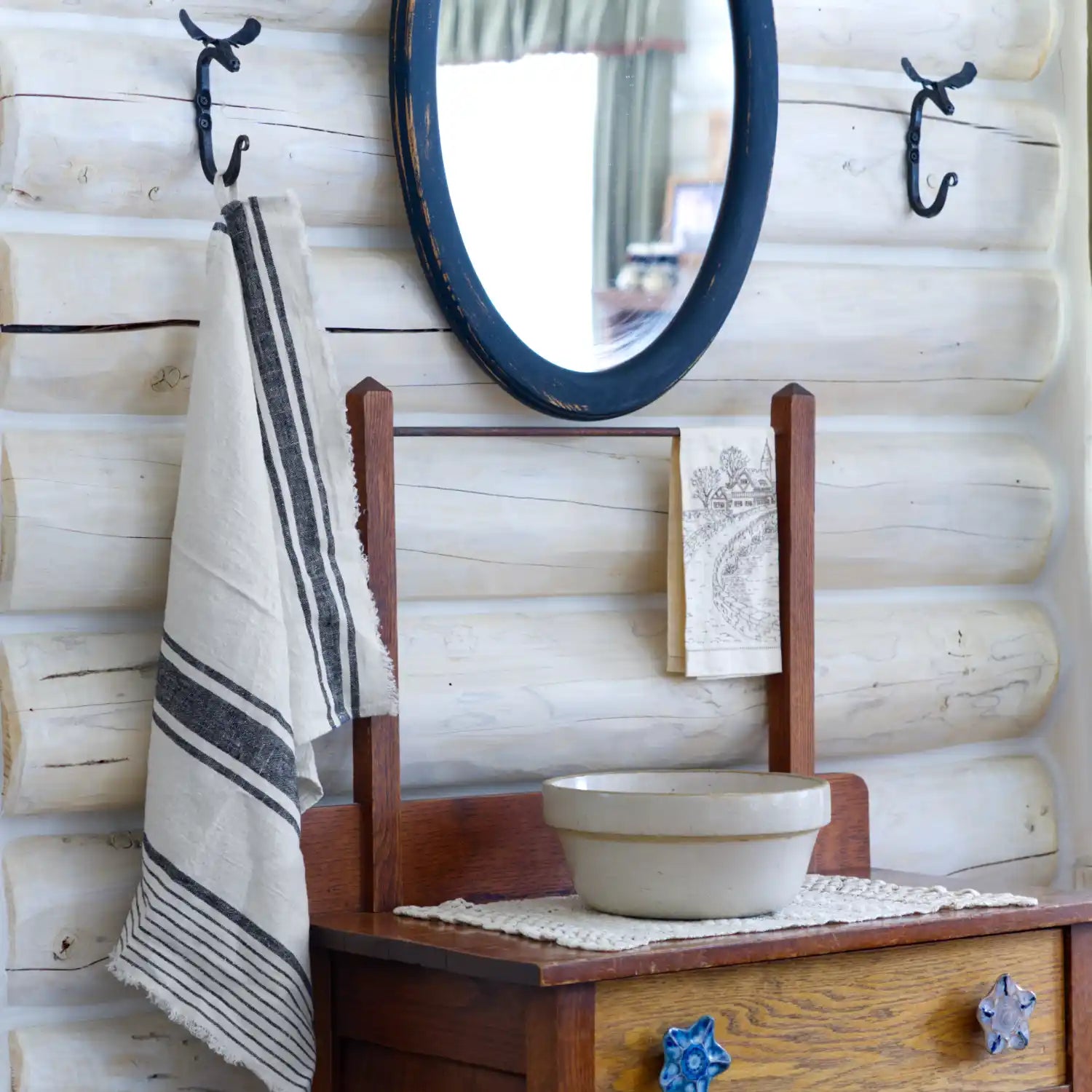 white and black stripe flax linen hand towel hanging from metal hook in log house