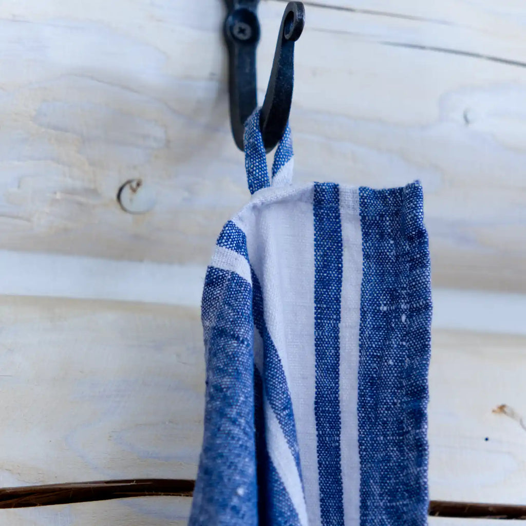 Blue and white stripe flax linen hand towel hanging from hook.