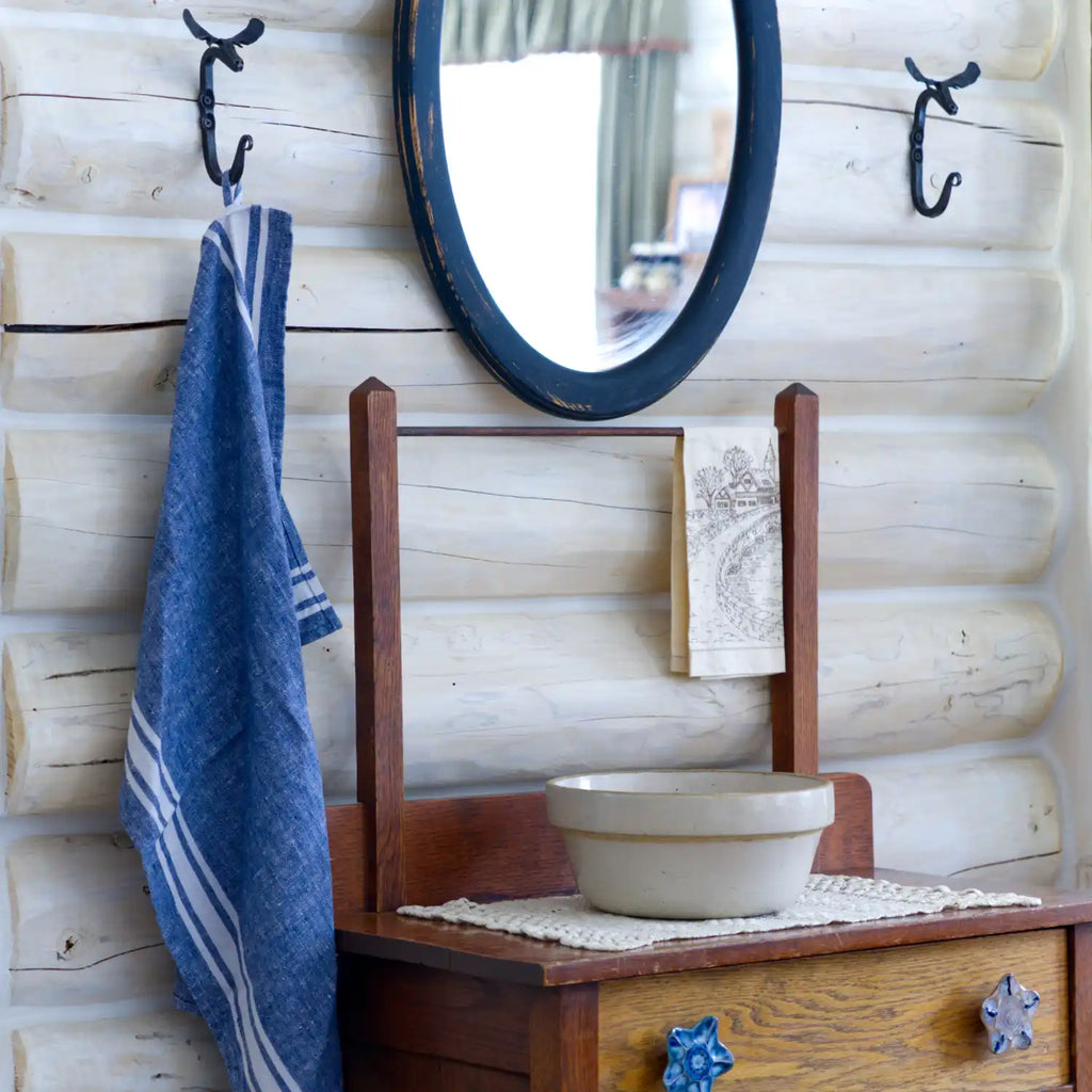 white and blue stripe flax linen hand towel hanging from metal hook in log house
