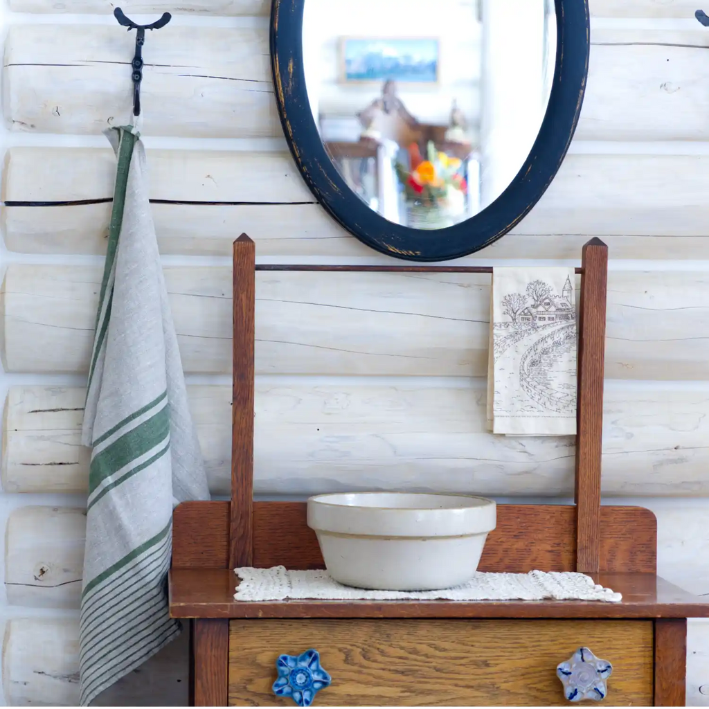 grey and green stripe flax linen hand towel hanging from metal hook in log house