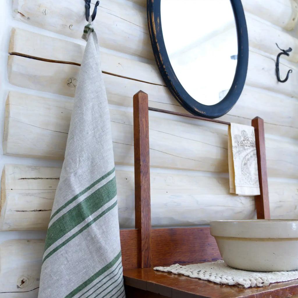 grey and green stripe flax linen hand towel hanging from metal hook in log house