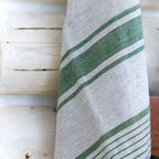 grey and green stripe flax linen hand towel hanging on log wall.