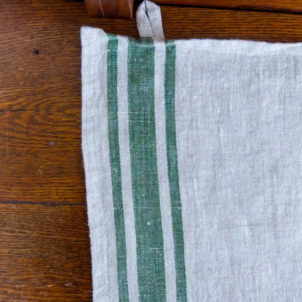 grey and green stripe flax linen hand towel laying flat on wood table.