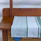 grey and green stripe flax linen hand towel laying flat on wood cabinet