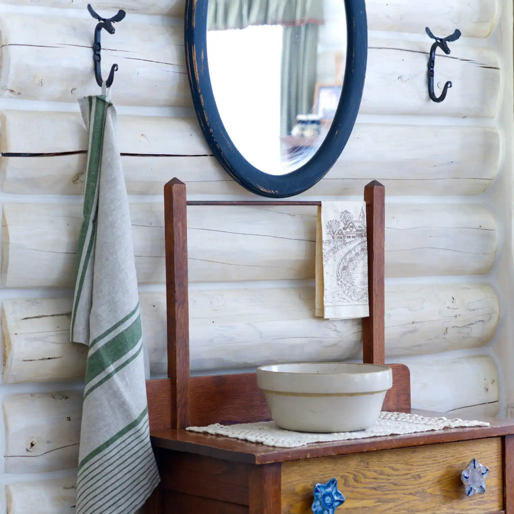 grey and green stripe flax linen hand towel hanging from metal hook in log house