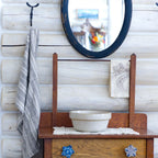 grey flax linen hand towel hanging from blacksmith hook in log house with a mirror and washstand beside.