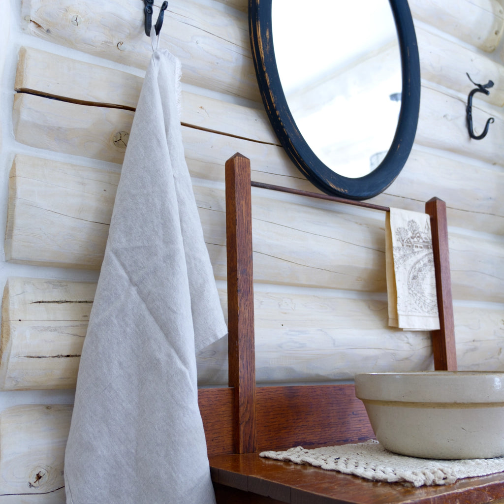 light natural frayed edge linen hand towel made from European flax. hanging from metal hook in log house.