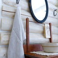 light natural frayed edge linen hand towel made from European flax. hanging from metal hook in log house.
