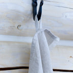 light natural frayed edge linen hand towel. Made form 100% flax. hanging on wall from metal hook in log house.