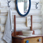 natural color frayed edge hand towel made from flax linen. hanging from metal hook in log house.