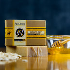 oatmeal honey goat milk soap sitting on table with rolled oats and a bowl of honey